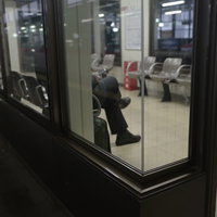 駅構内のホームにある待合室でベンチに座って電車を待つ乗客たちの写真