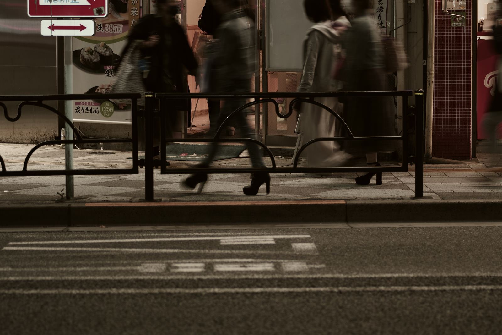 夜の歩道を歩く複数の人々の足元を写した写真