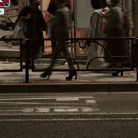 歩道を行き交う人々の足元と移動する通行人たちの写真