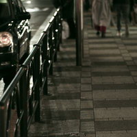 夜間の歩道で車のヘッドライトが反射するガードレールの写真