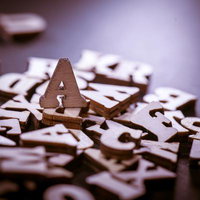 木製のアルファベット文字が散らばる中でAの文字が立つパスワード風景の写真