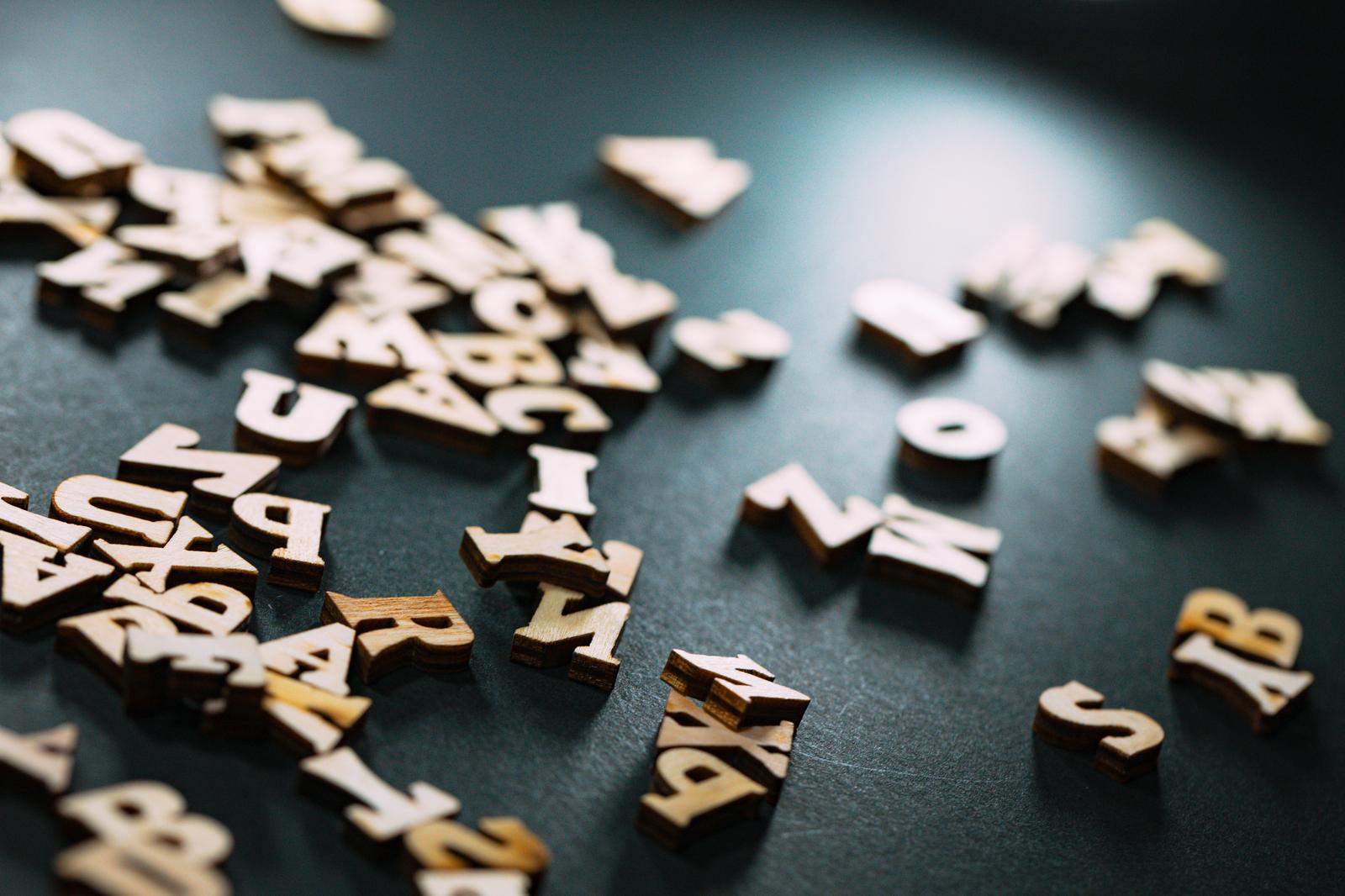 紺色の背景に散らばった木製の英文字と数字