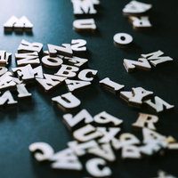 木製のアルファベットと数字が黒い背景に散らばるの写真