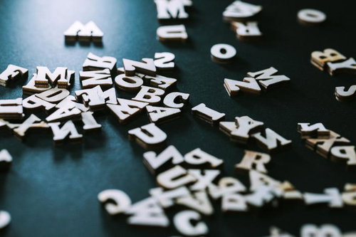 木製のアルファベットと数字が黒い背景に散らばる