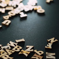 ダークグレーの背景にランダムに散らばるアルファベット文字の写真