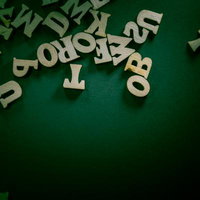 緑の背景に浮かぶ木製の英文字とアルファベットの写真