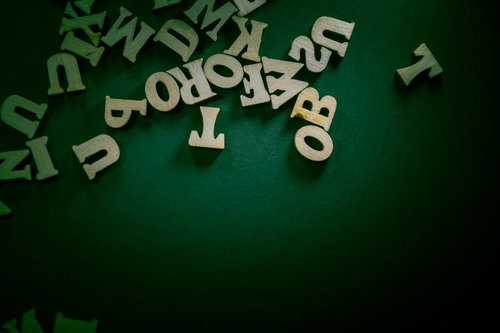 緑の背景に浮かぶ木製の英文字とアルファベット