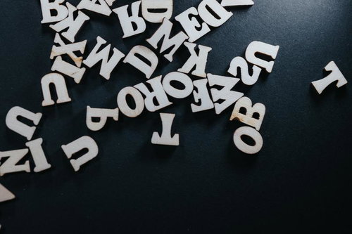 黒い背景に散らばる木製アルファベットパーツ