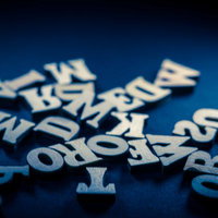 青い背景に散らばる木製アルファベット文字パーツの写真