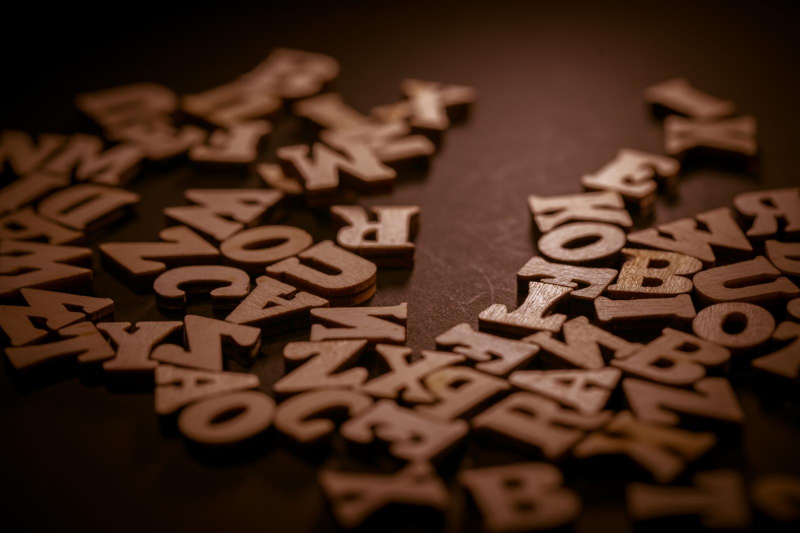 黒い背景に散らばる木製のアルファベットと数字のブロック