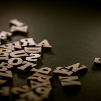 暗がりに散らばる木製アルファベット文字パーツの写真