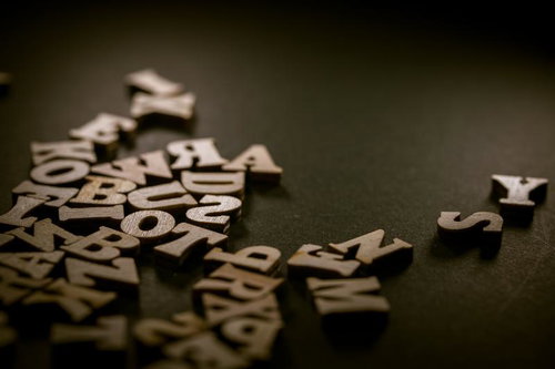 暗がりに散らばる木製アルファベット文字パーツ