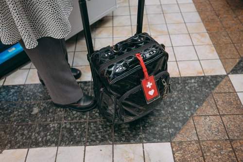 ヘルプマーク付き黒色キャリーケースを引く女性の足元