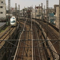 都会の線路を走る電車の写真