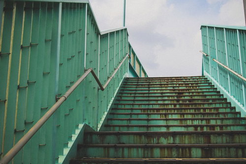 経年劣化で錆が目立つ歩道橋の階段と手すりの写真