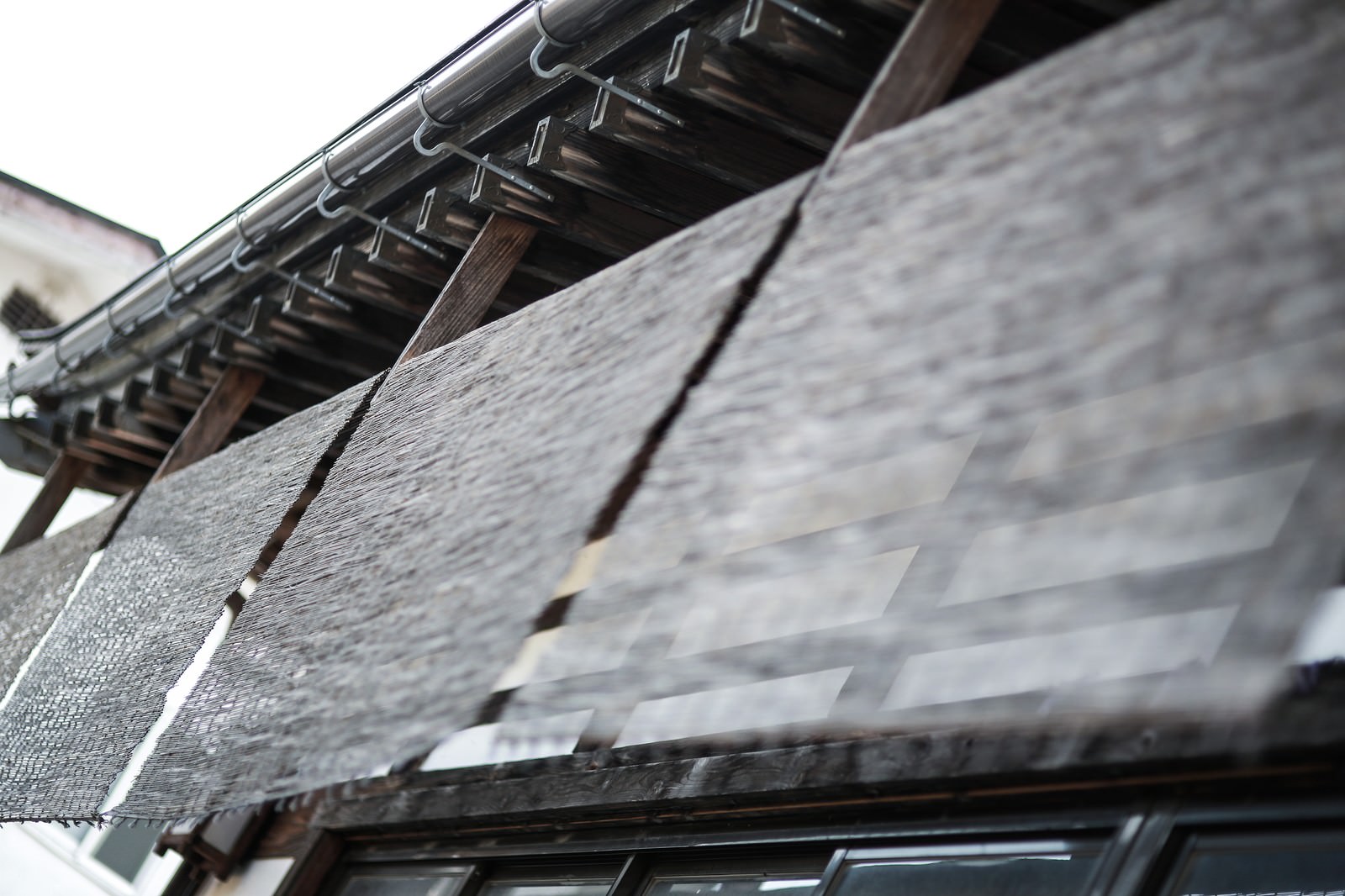 店先に掛けられた木製のすだれと瓦屋根の和風建築
