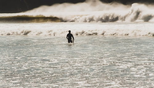 冬の高波に向かうサーファー、ウェットスーツ姿で海に挑む