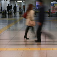 電車通勤時の改札前を歩く会社員たちの様子の写真