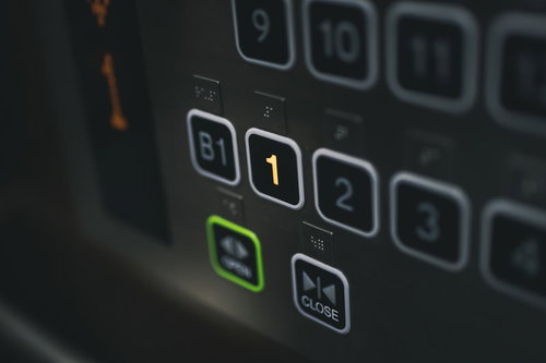 エレベーターの1階行きボタン、緑色に光った操作パネル