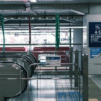 駅構内のエスカレーター前に設置された金属製の手摺りの写真