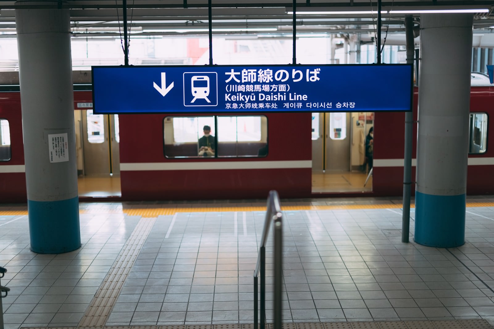 大師線のりばの案内看板が掲げられた駅ホームに赤い電車が停車している