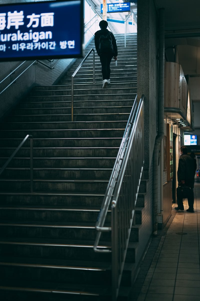 薄暗い駅構内で階段を上る男性のシルエット