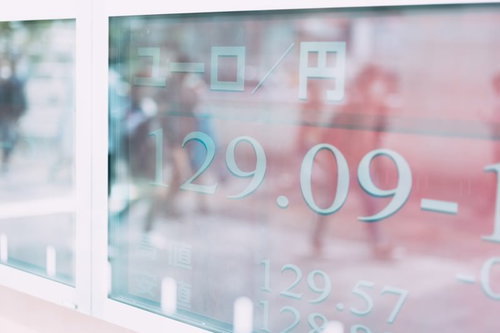 通行人のシルエットが映り込む為替モニターの電光掲示板