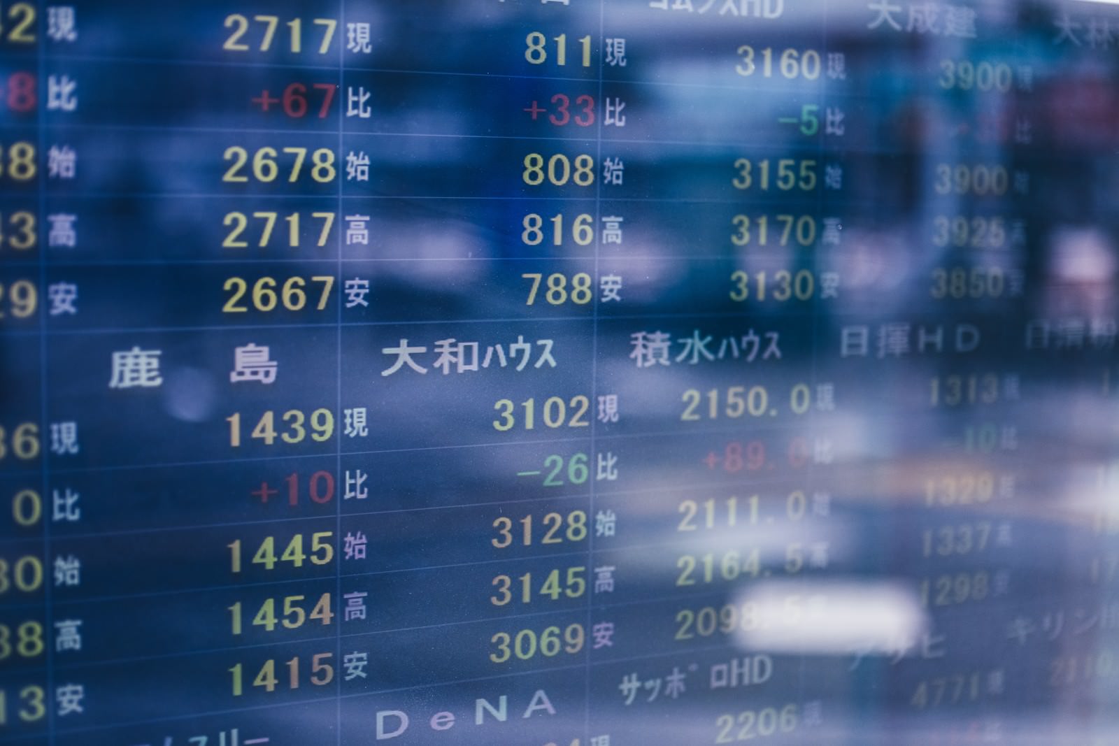 青い光で照らされた電光掲示板に表示される株価や相場の数値データ