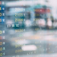 株価の電光掲示板がガラス面に反射する取引画面の写真