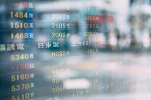 株価の電光掲示板がガラス面に反射する取引画面