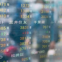 株価の電光掲示板に映る通行人の影 金融市場と日常風景の写真
