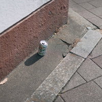 歩道に置き忘れられた白い空き缶とポイ捨て問題の写真