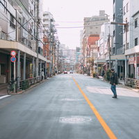 商店街の車道に飛び出した通行人と建ち並ぶ店舗の写真