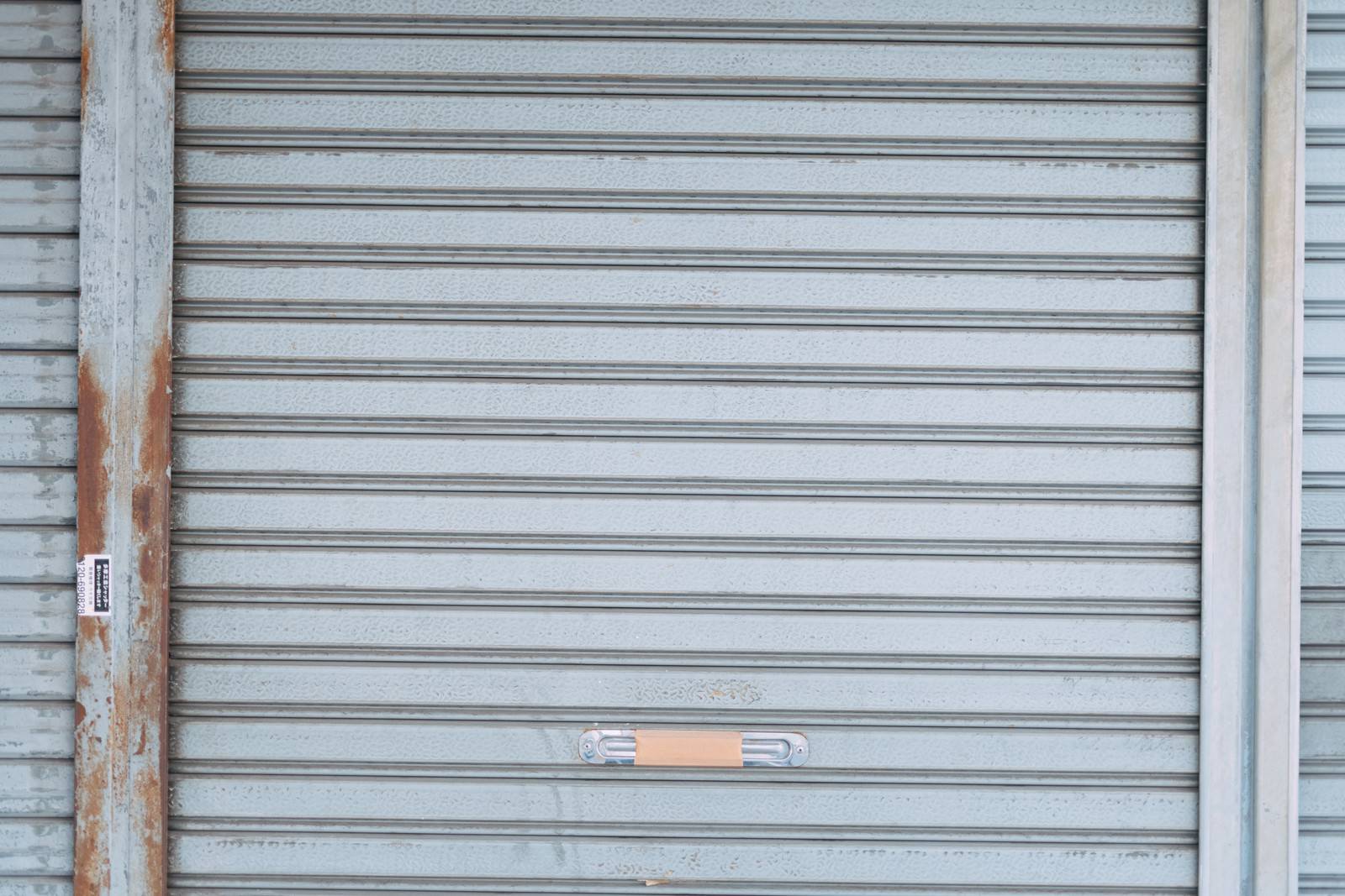 グレーの金属製シャッターが閉じられた状態で、横縞の模様が規則的に並んでいる