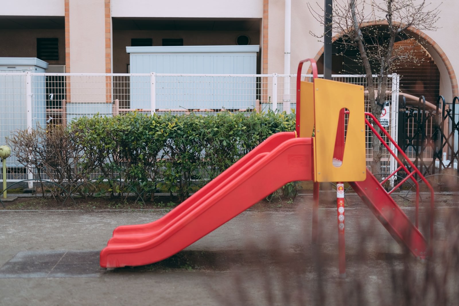 公園に設置された赤い滑り台と黄色い階段の幼児向け遊具