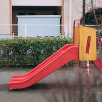 児童公園に設置された赤と黄色の幼児向け滑り台の写真