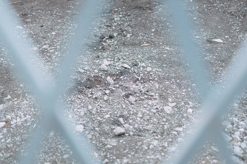 フェンス越しに見る灰色の砂利が敷かれた地面