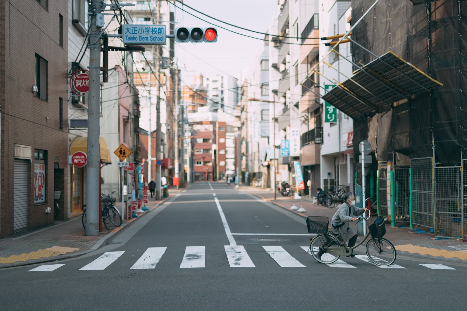 住宅街の道路で自転車を押しながら横断歩道を渡る人