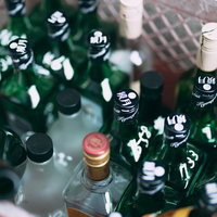 焼酎の空き瓶が積み重なる山、緑色ボトルが層状に保管された光景の写真