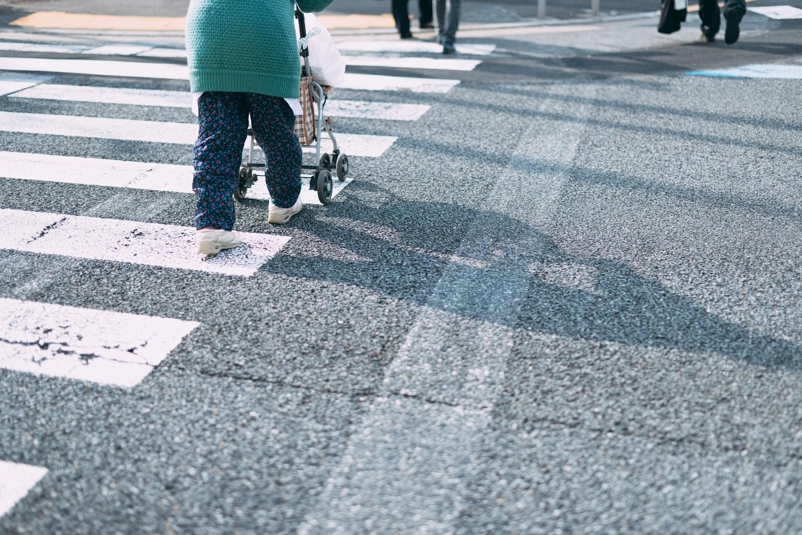 手押し車を押して横断歩道の白いストライプの上を歩く人