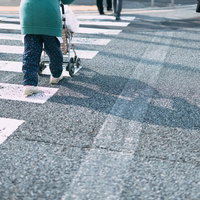 手押し車を押して横断歩道を渡る高齢女性の写真