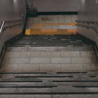 地下へと下る暗いコンクリート階段と金属製手すりの写真