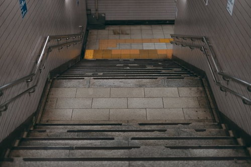 地下へと下る暗いコンクリート階段と金属製手すり