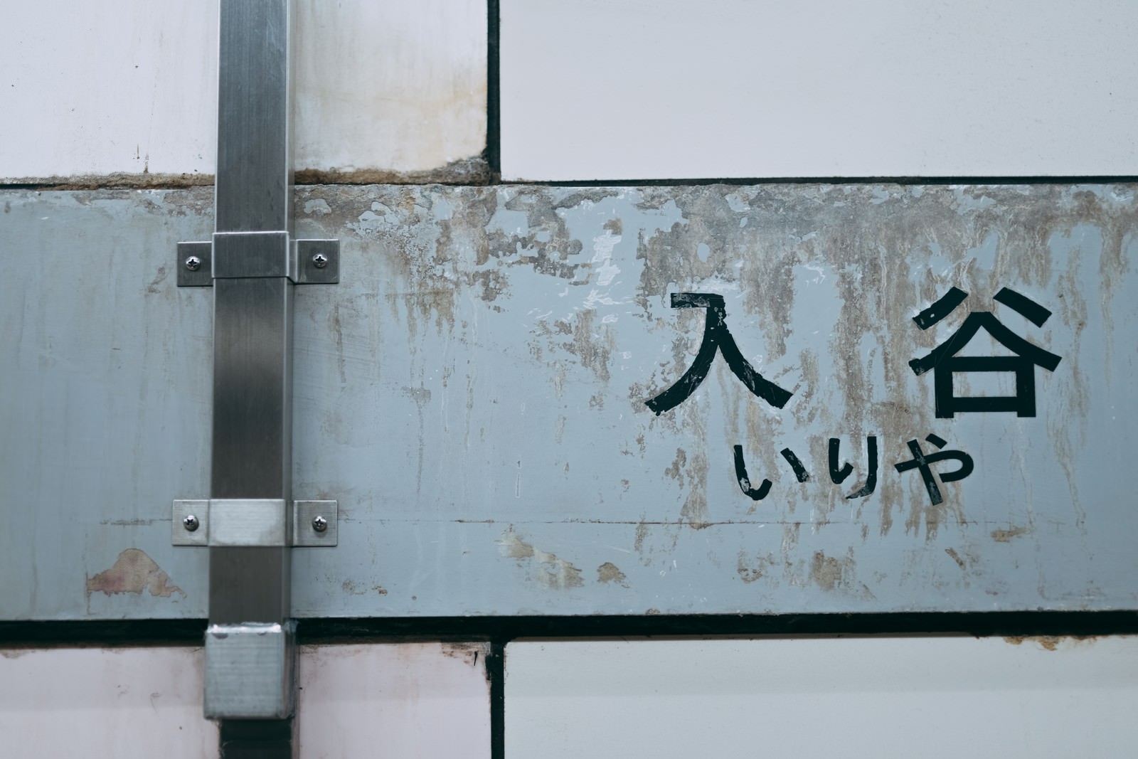 白い背景に青い文字で入谷と書かれた看板