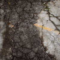 ひび割れが進んでボロボロになった駐車場のコンクリートの写真