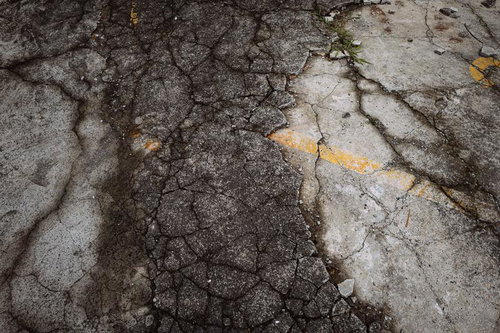 ひび割れが進んでボロボロになった駐車場のコンクリート