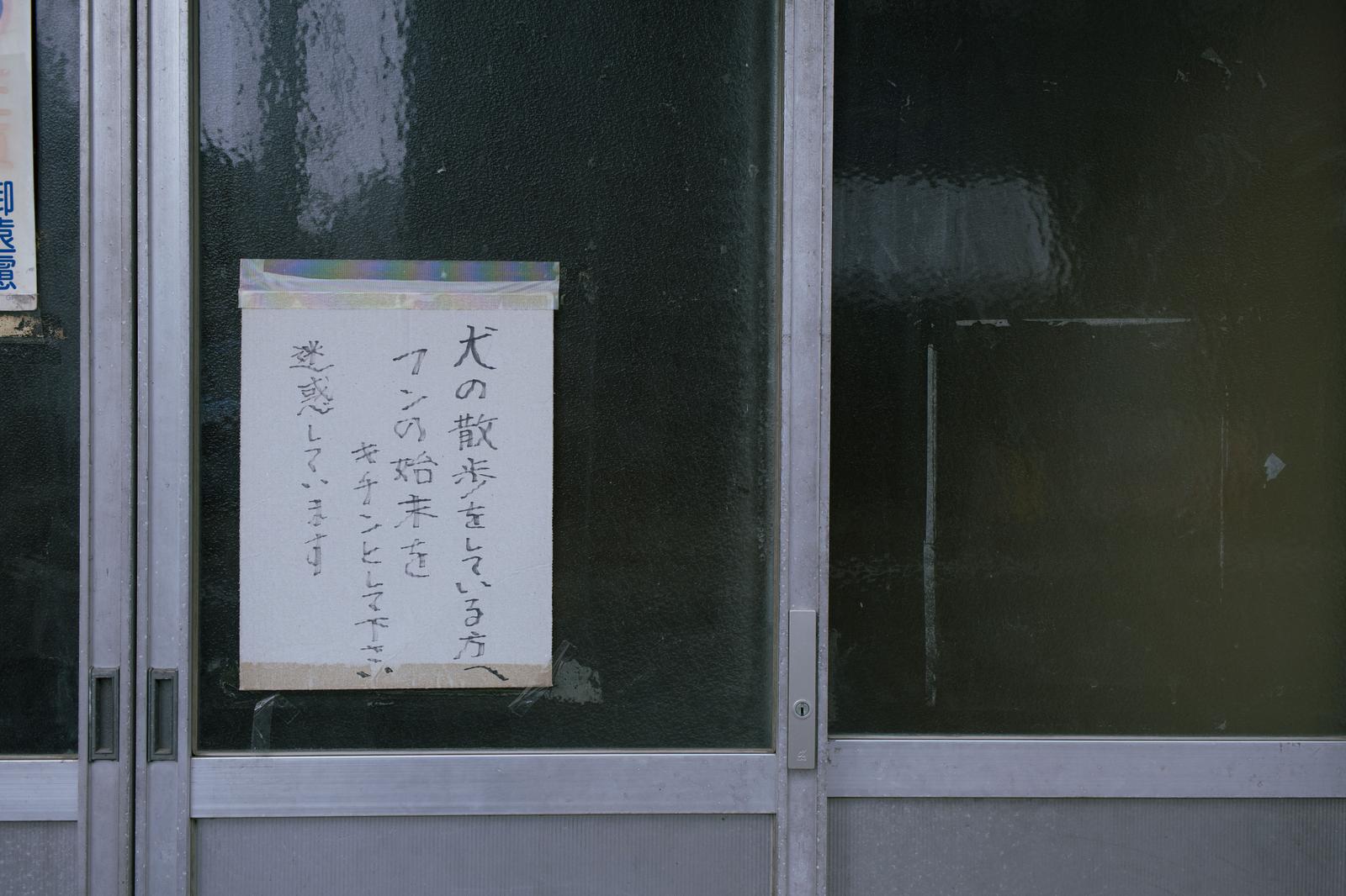 引き戸にクリップで固定された手書きの注意文が貼られている