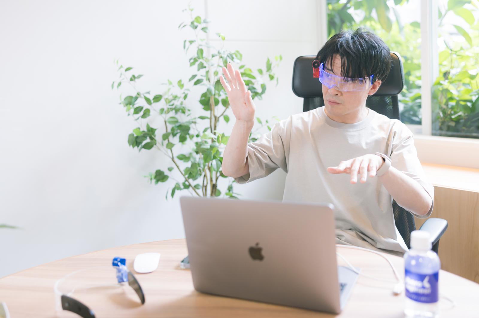 ARグラスを装着してジェスチャー操作する男性エンジニア［モデル：金子周平］