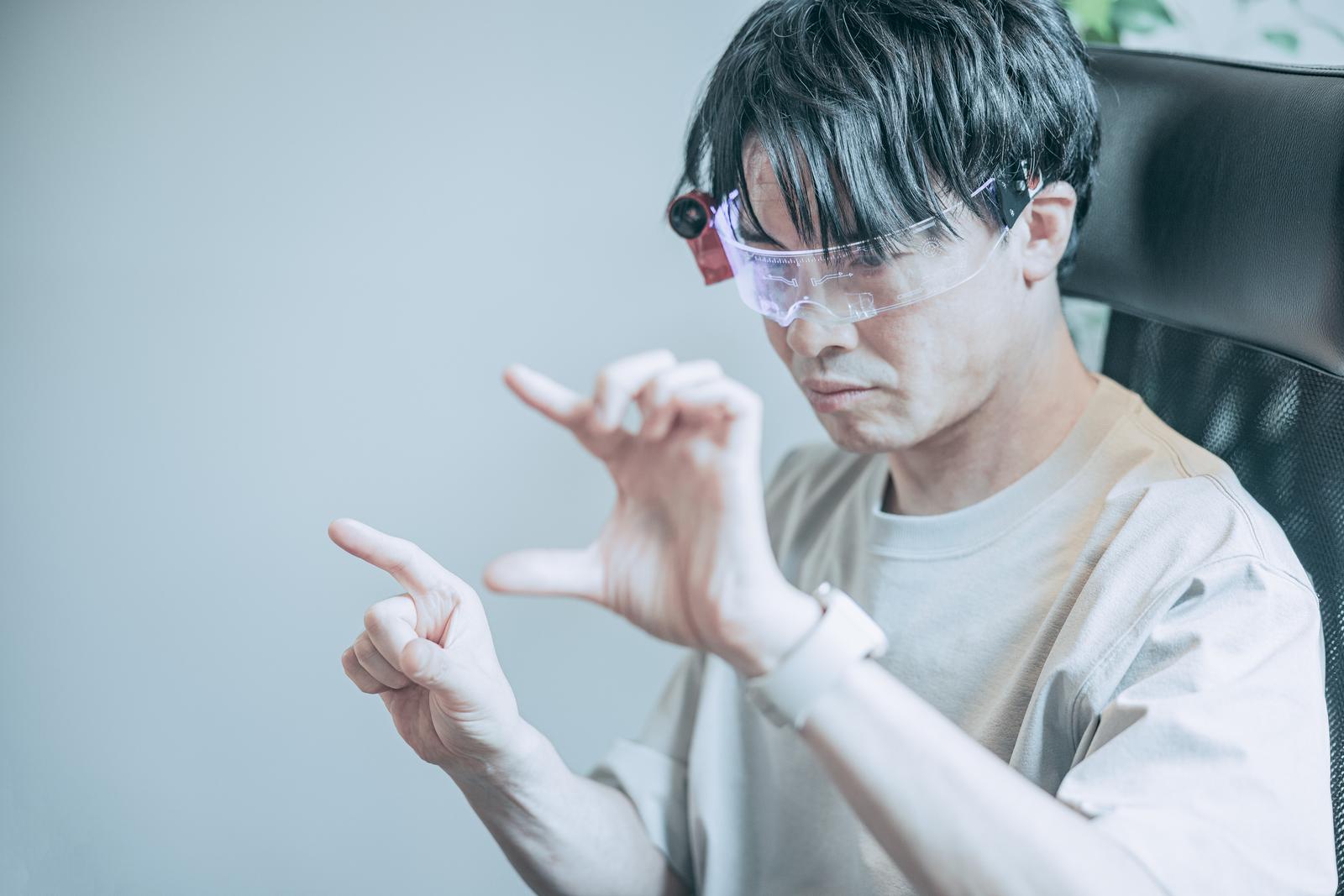ARグラスをつけてピンチイン操作するエンジニア男性が真剣な表情で両手を動かしている［モデル：金子周平］