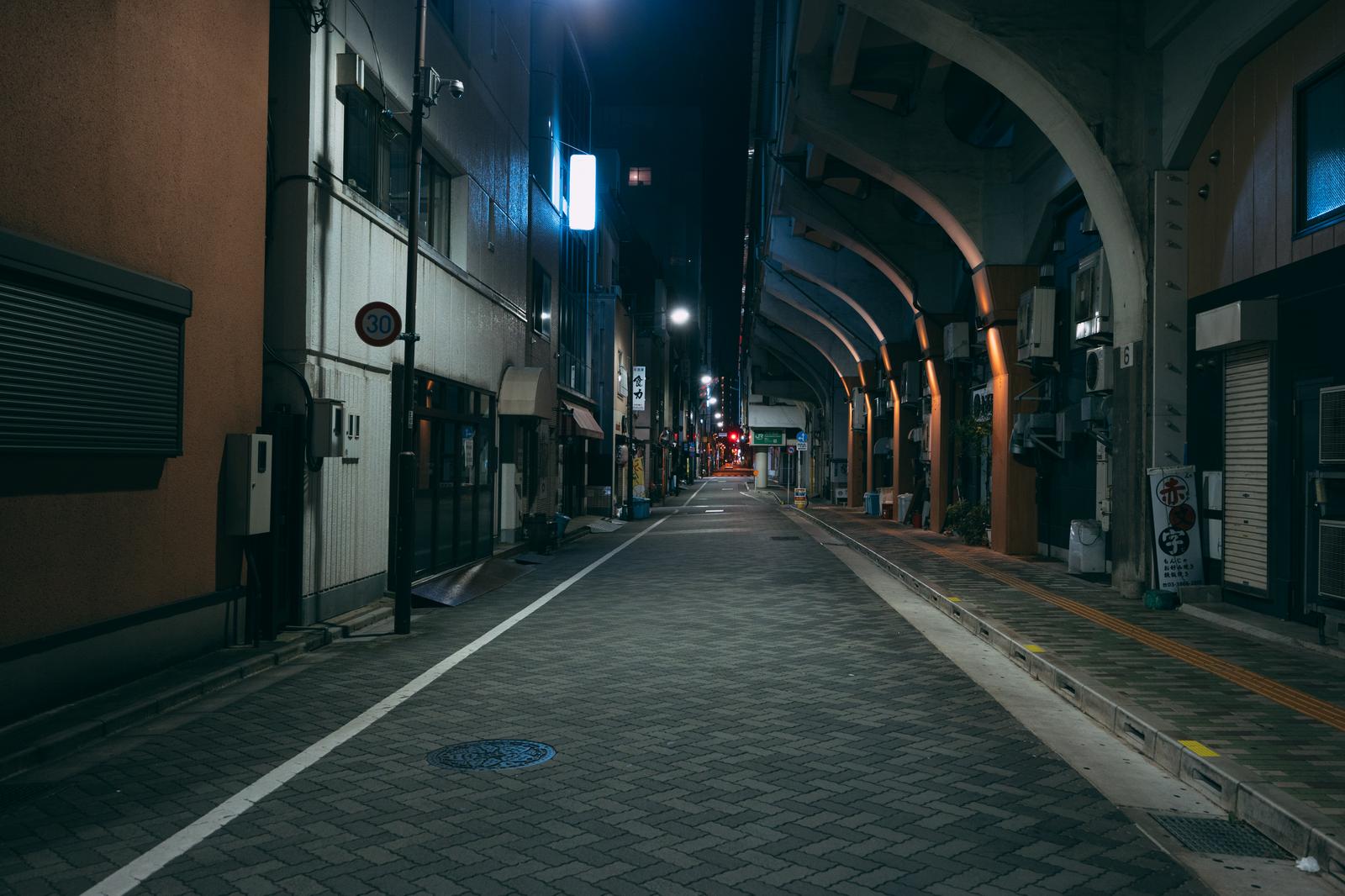 深夜の浅草橋高架下。両側に閉じたシャッターの店が並び、街灯に照らされた無人の通り